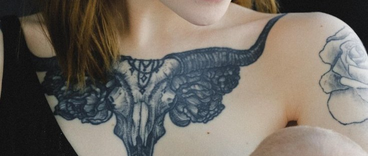mujer rubia con tatuajes amamantando bebe